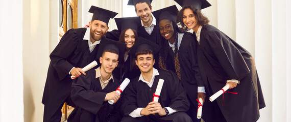 Portrait of a smiling happy multiracial international graduates students standing in a university...