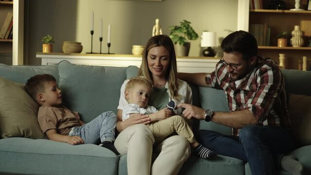 Married couple sitting on sofa at home, talking to their children. Loving parents spend enough time together with kid