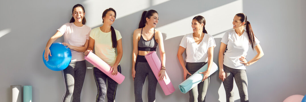 Happy young spoty girls before, after sport class, fitness group workout friends together with coach. Smile celebrate healthy, active lifestyle sport studio, enjoy good body shape, holding mat, ball