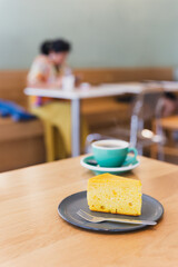Slice of homemade sponge cake with cup of coffee on table.