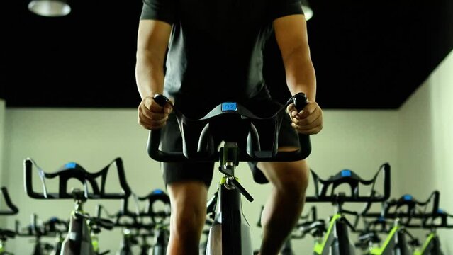 Fit and healthy man cycling on exercise bike in indoor fitness gym. cardio and endurance sports concept.