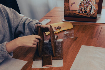 Hands holding walls of gingerbread cookies house. Christmas concept