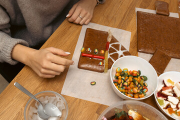 Design of gingerbread cookies house, female hands
