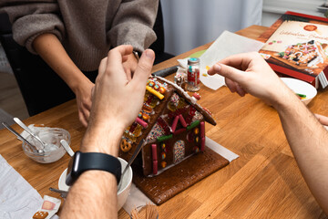 Young woman and man painted with sugar gingerbread cookies house