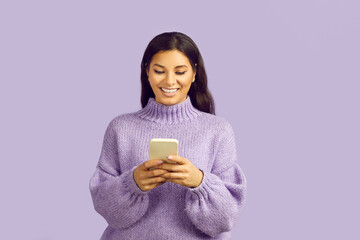 Satisfied woman types sms on modern mobile phone or enjoys good internet connection. Smiling...