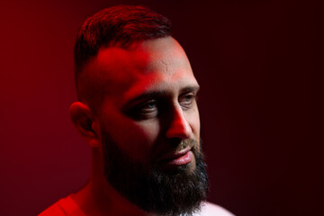 Studio portrait with colorful light of young handsome bearded man.