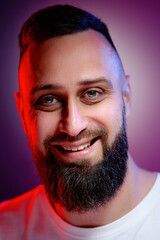 Obraz premium Studio portrait with colorful light of young handsome bearded man.