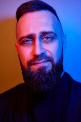 Studio portrait with colorful light of young handsome bearded man.