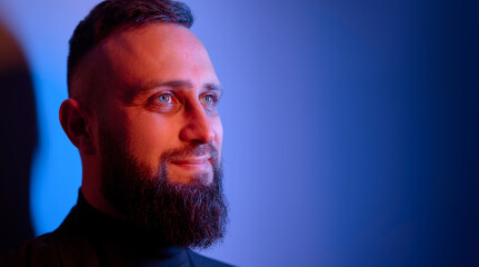 Studio portrait with colorful light of young handsome bearded man.
