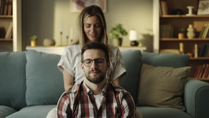 Beautiful young wife massaging her husband's neck and shoulders in slow-motion. Happy couple spending time together - Powered by Adobe