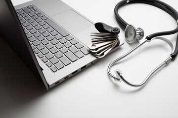Tool and stethoscope on laptop, closeup. Concept of technical support