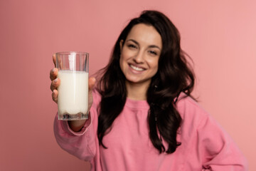 Smiling friendly dark-haired cute young woman showing in front of the camera her favorite dairy beverage. Healthy drink consumption concept