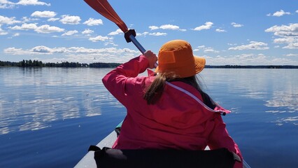 A girl kayaking on a lake on a sunny day.
