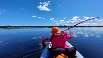A girl kayaking on a lake on a sunny day.
