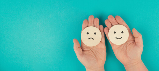 Holding a head with a sad and a happy face in the hands, mental health concept, positive and...