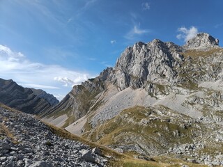 Peak Bobotov Kuk in Montenegro. Grey rocks on a sunny day against a blue sky. The slopes are...