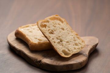 sliced ciabatta bun on wood board closeup