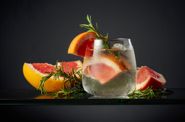 Cocktail gin tonic with ice, grapefruit, and rosemary.