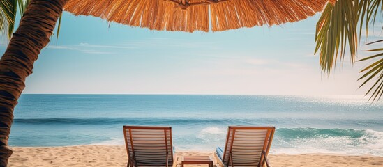 Two lounges under an umbrella with palm leaves by the sea. Creative banner. Copyspace image