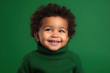 A smiling baby wearing a green sweater