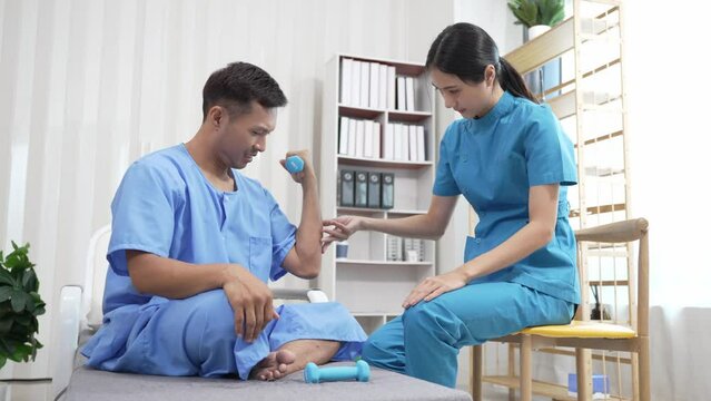 A nurse helps with physical therapy for a male patient at the hospital. Asian male patient receives treatment at medical relief clinic Health insurance concept