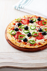 Pizza with salami, jalapeno pepper and black olives. Home made food. Concept for a tasty and hearty meal. Close up.