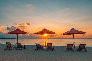 Beautiful tropical sunset scene, couple sun beds loungers, umbrella under palm tree. White sand, sea view with horizon, colorful twilight sky, calmness and relaxation. Inspirational beach resort hotel