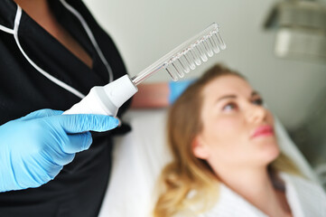 A dermatologist trichologist performs the procedure with a darsonval device to improve the...