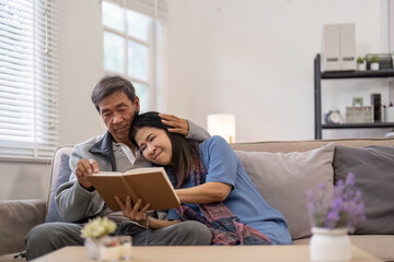Elderly couple reading book together on couch, Concept of companionship and love
