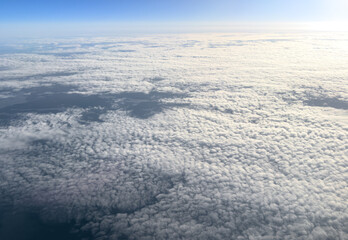 Fototapeta premium Aerial view white clouds in blue sky. Aerial top view cloudscape. Texture of clouds. View from above. Sunrise or sunset over clouds. Panorama sky