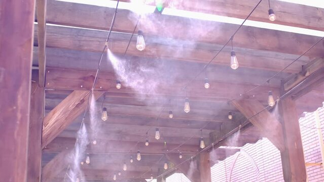 Water spray system for cooling the terrace on a hot summer day. Fogging system, high pressure water spray. Wooden ceiling in loft style.