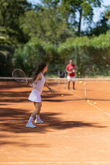 A woman is playing tennis on a clay court