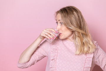 Young Woman Drinking Water from Plastic Cup on Pink Background