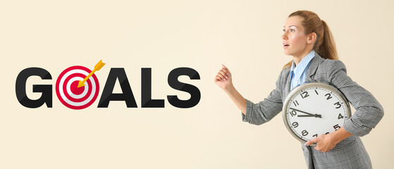 Running young businesswoman with clock on light background