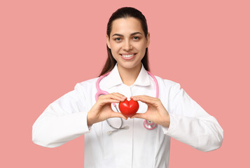 Portrait of female doctor with heart on pink background