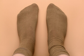 Female legs in brown socks on beige background