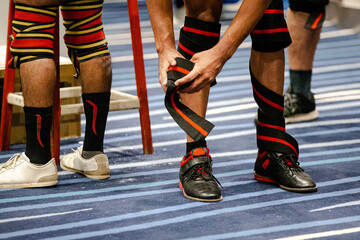 knees of powerlifters in knee elastic wraps before squat powerlifting