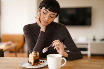 thinking woman eating chocolate cake and drinking hot drink 
