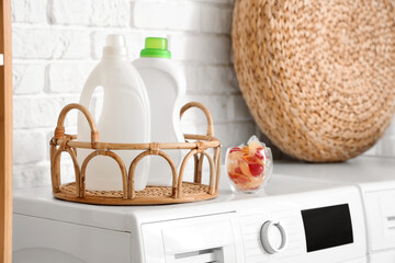 Bottles and capsules of laundry detergent on washing machine, closeup