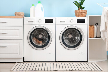 Interior of modern laundry room with washing machines and bottles of detergent