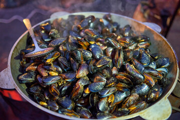 Street food. Boiled mussels with herbs at a fair.