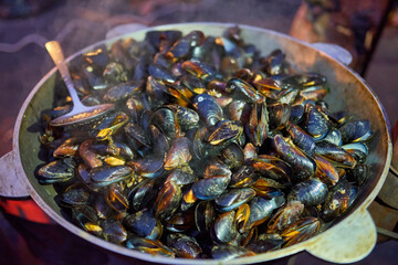 Street food. Boiled mussels with herbs at a fair.