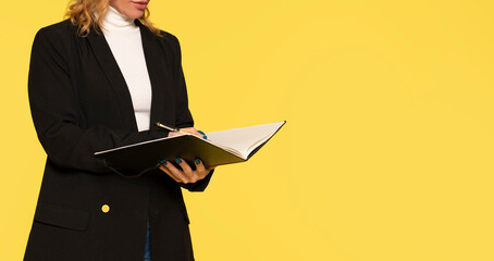 part of body woman with pen writing  to folder on yellow background