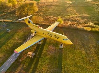 Yellow passenger plane stands in the field. Top view with a drone