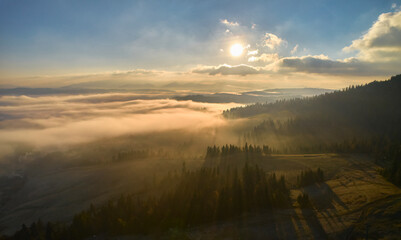 Flight over fog in Ukrainian Carpathians in summer. A thick layer of fog covers the mountains with a continuous carpet. Aerial drone view.