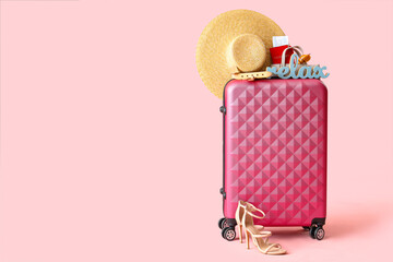 Suitcase with beach accessories, stylish shoes, passport and decor on pink background