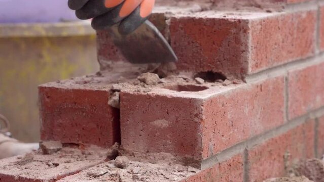 hands of Builder breaking brick wall with chisel and hammer