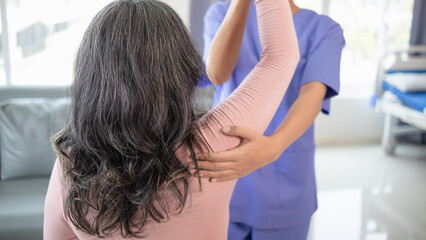 female doctor is helping a patient move her muscles after recuperating from a muscle injury and...