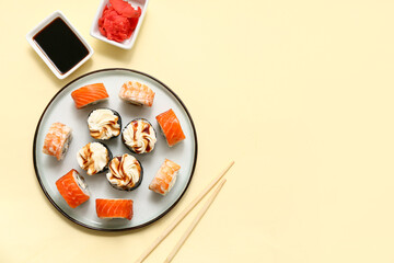 Tasty sushi rolls with chopsticks, marinated ginger and soy sauce on light yellow background