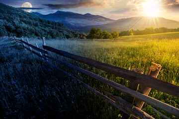 wooden fence across the grassy rural field at summer solstice. mountainous countryside scenery...